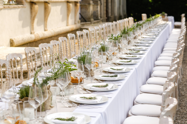 A large banquet table set full of glassware, plates, linens and more